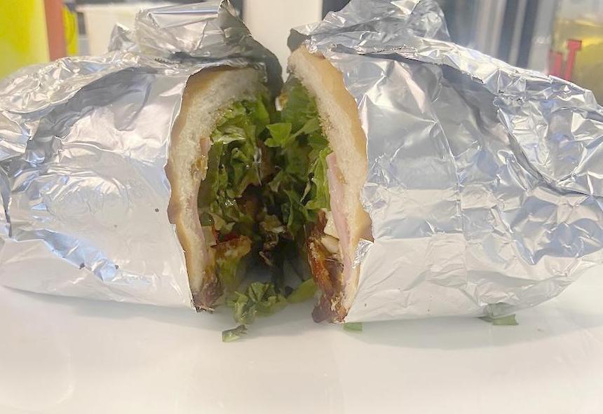 A sandwich cut in half and wrapped in foil, ready to go